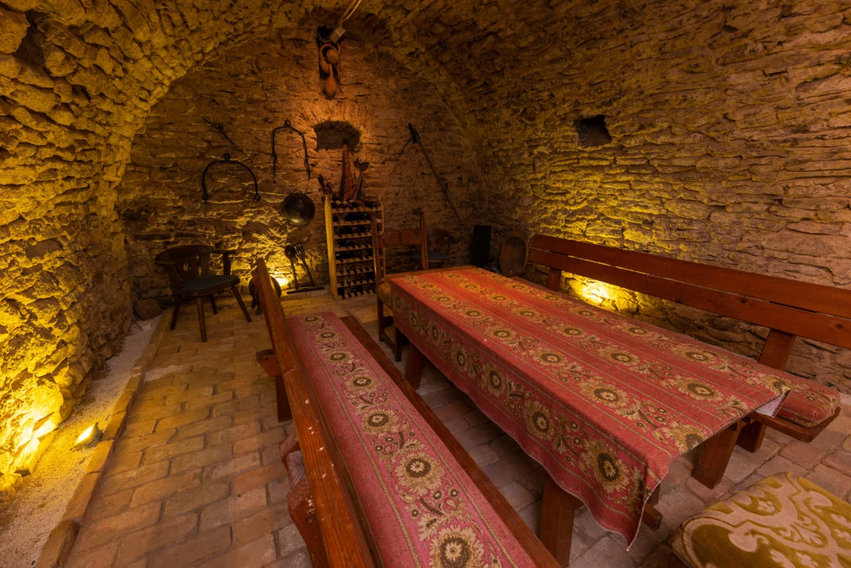 Historischer Gewölbekeller der Tabódy Villa mit langem Tisch und Sitzbänken aus seitlicher Perspektive
