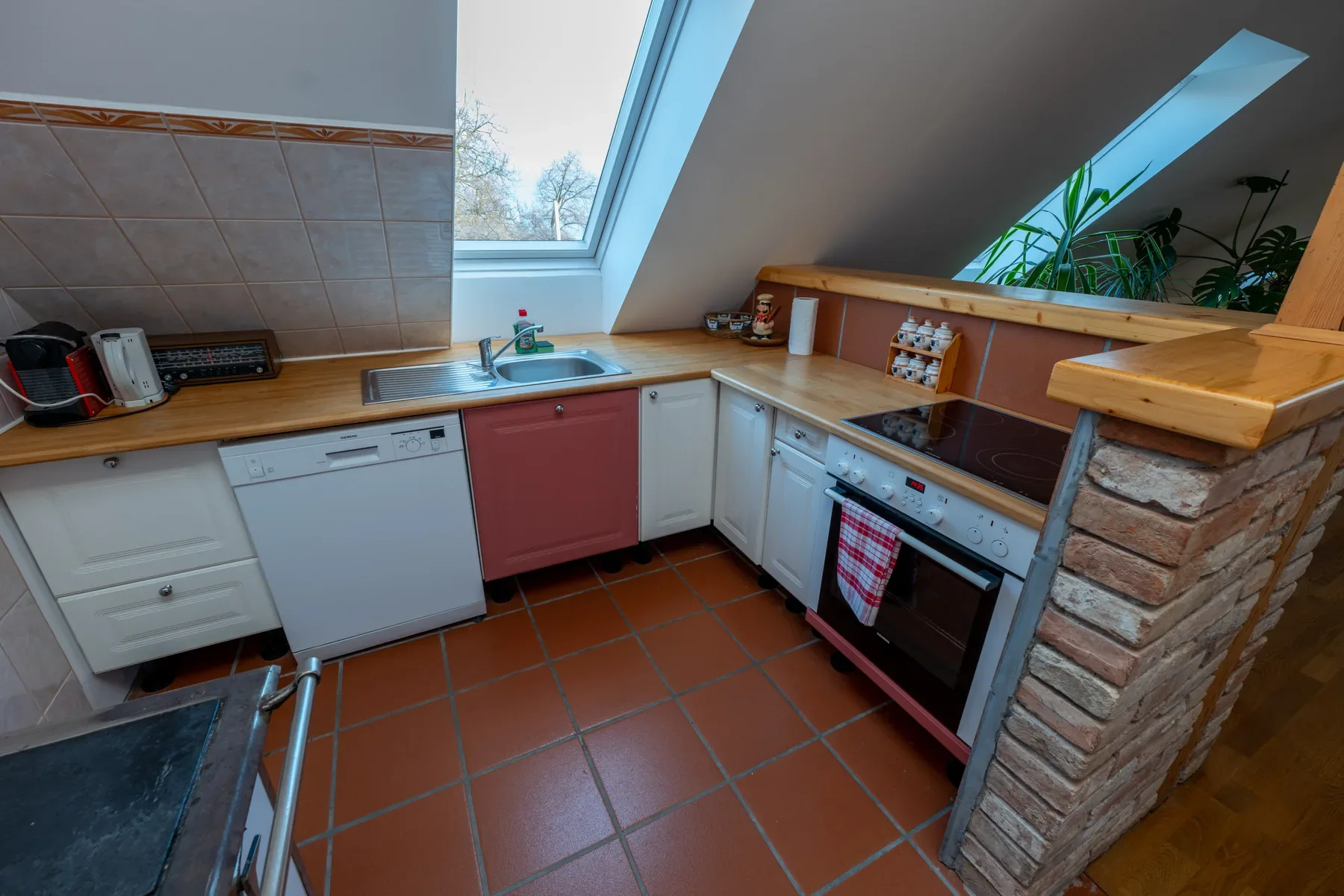 Küche im Apartment Modern mit weiß-roten Fronten, Dachfenster und offenem Übergang zum Wohnbereich