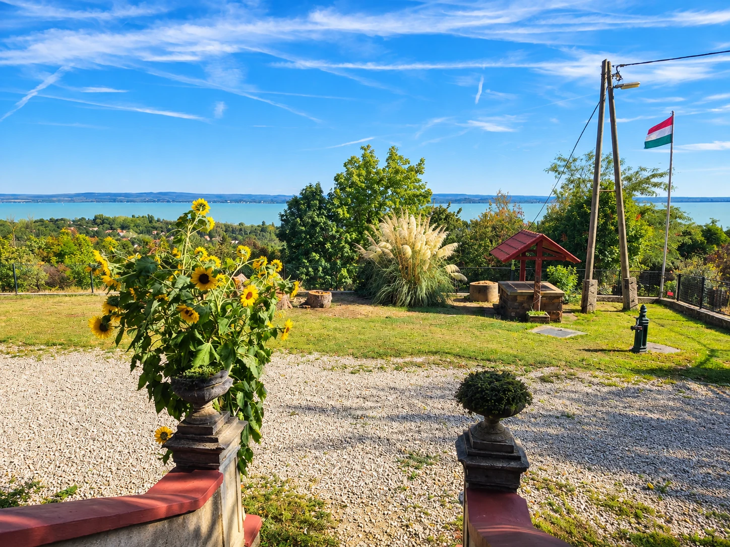 Garten der Tabódy Villa mit Blumen, Feuerstelle und Blick auf den Balaton