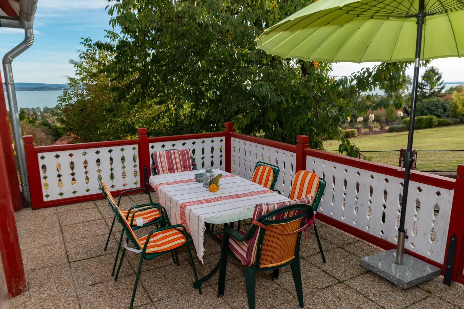 Gemeinsame Gartenterrasse der Tabódy Villa mit Esstisch, Sonnenschirm und Blick auf den Balaton